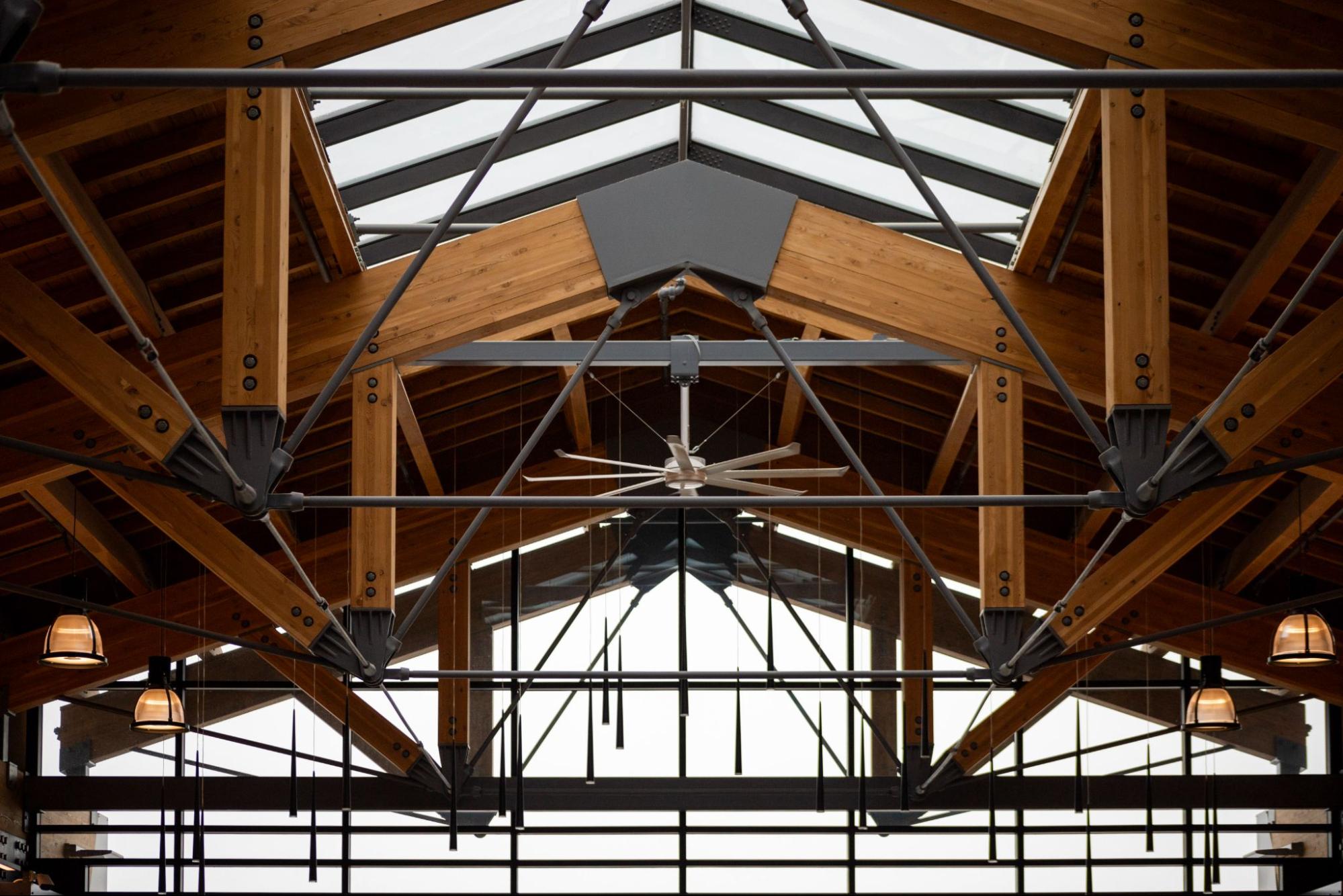 This image shows the interior view of the building ceiling highlighting exposed wooden beams paired with sleek metal supports, creating a sleek and sophisticated look.