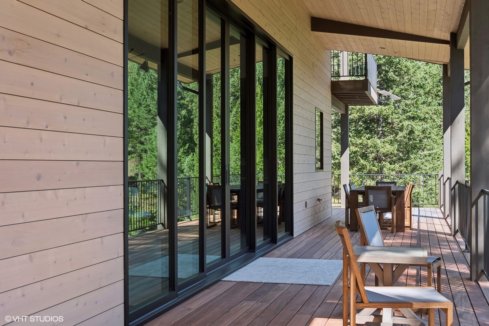 This image shows a home exterior featuring wood siding and a large sliding glass door, creating a seamless transition between indoors and outdoors.