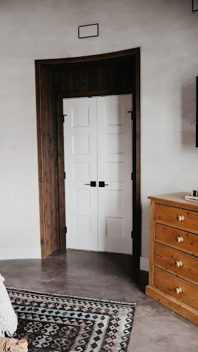 This image depicts a cozy bedroom with a dark wood accent wall highlighting the entryway door, adding depth to the space.